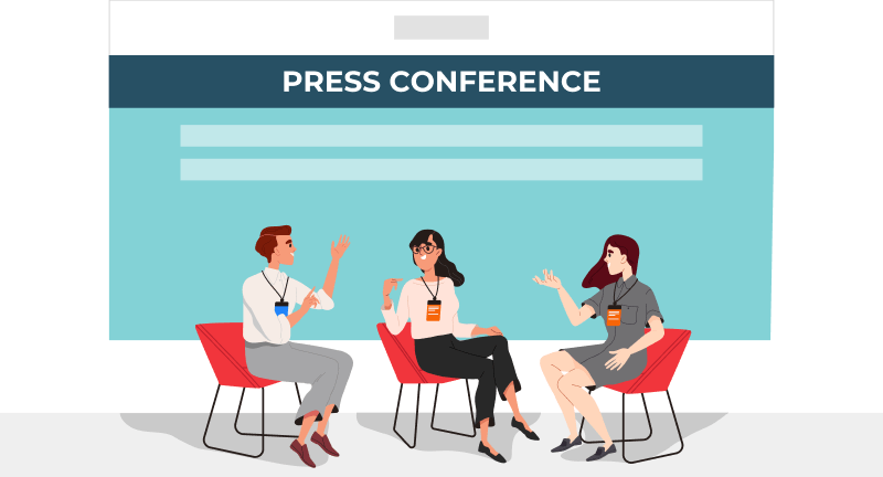 Three professionals are discussing, with a backdrop of a presentation screen.​